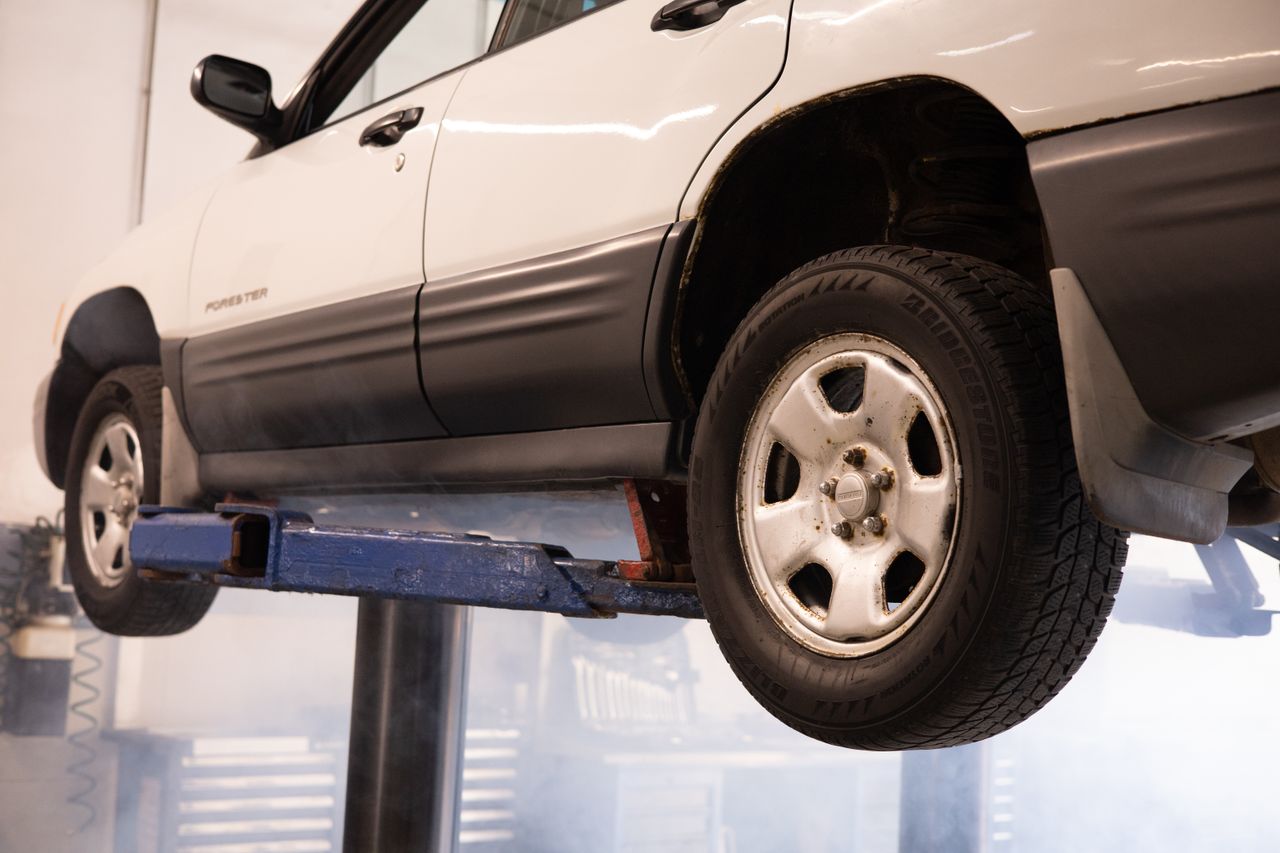 The Art of Drawing Readers In: Your attractive post title goes here A white car suspended on a lift in an automotive repair shop, showcasing maintenance work.